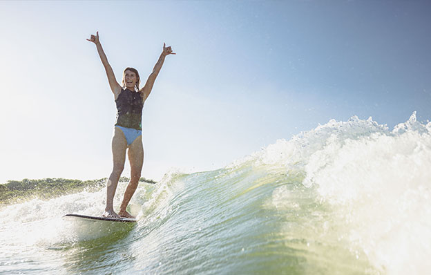 Girl throws up hands while surfing